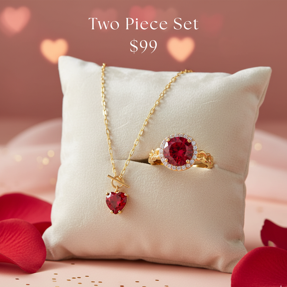 Two-piece jewelry set with necklace and ring featuring red gemstones on a white pillow with heart-shaped background.
